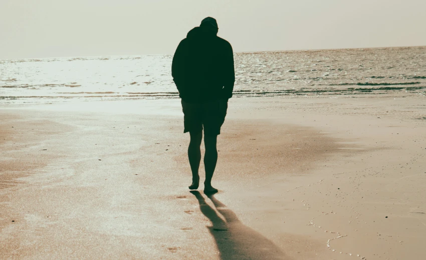 Person walking on beach at sunset, symbolizing Leadership and the Potere dei Piccoli Passi through steady progress.