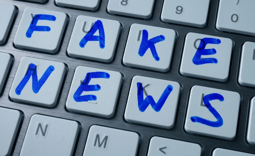 Un’immagine ravvicinata di una tastiera di un portatile Dell. Le lettere "FAKE NEWS" sono scritte in lettere blu, scritte a mano, direttamente su otto dei tasti di plastica bianca della tastiera. Le parole appaiono come se fossero state scritte con un pennarello indelebile. La tastiera stessa ha un involucro grigio metallizzato e una leggera tinta bluastra. Sullo sfondo ci sono altre chiavi, la cui scrittura è leggermente sfocata ma leggibile. L'immagine si concentra sull'effetto delle notizie false sulla reputazione.